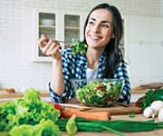 Woman eating green salad as to consume fewer calories for immune health