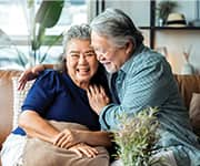 Senior husband and wife hugging on couch at risk of Alzheimer's disease