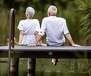 Senior couple sitting on deck over water