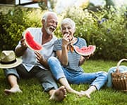 Senior couple eating watermelon laughing together