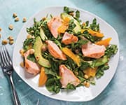 Salmon, avocado, orange, and watercress salad on a white plate