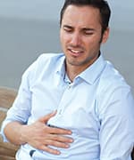 Man holding stomach due to bloating and abdominal pressure