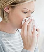 Women sneezing into tissue due to the common cold