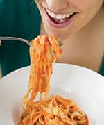 Woman eating bowl of pasta in red sauce