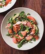 Salmon, avocado, and watercress salad on white plate