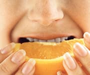 Woman taking bite out of orange slice for natural vitamin C