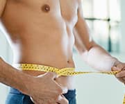 Man measuring waist with measuring tape for weight loss progress