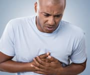 Man clutching chest, in pain after a heart attack