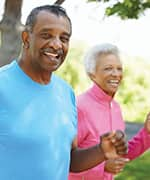 Senior husband and wife jogging in park for increased life-expectancy