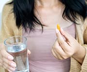 Woman holding a glass of water and a supplement of bioavailable curcumin