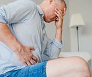 Man hunched over in discomfort due to chronic liver disease